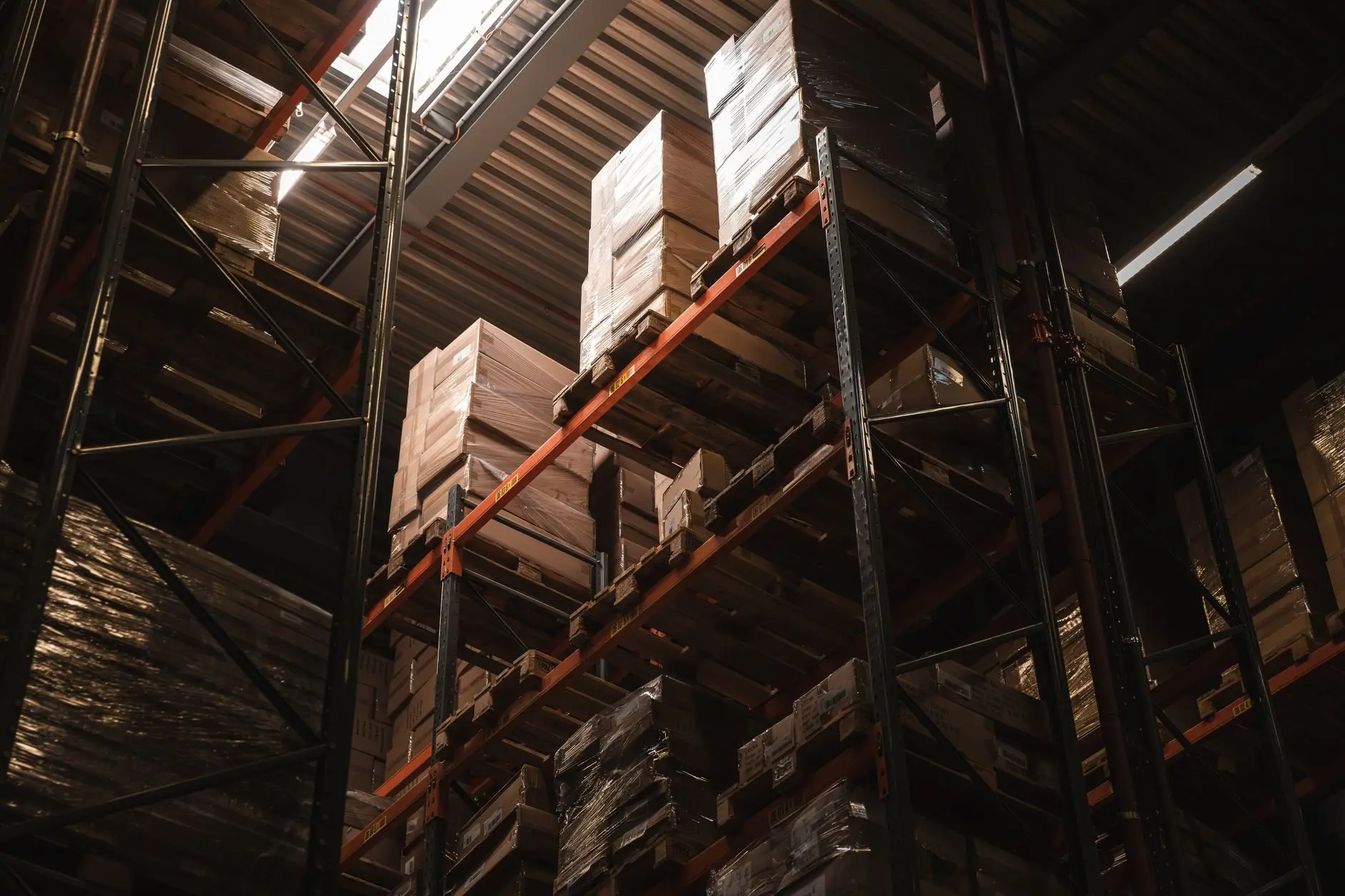 Refrigerated warehouse aisle with high-bay pallet racking, strip curtains and frost on packaging